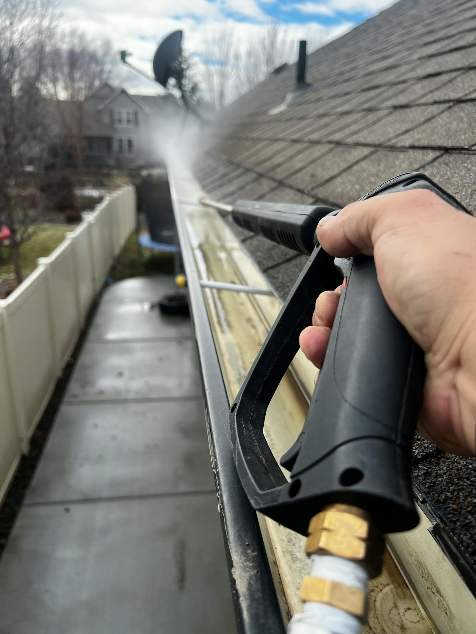 Dirty gutter with debris being pressure washed before whitening